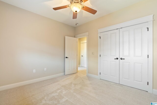 unfurnished bedroom with a closet, light colored carpet, and ceiling fan