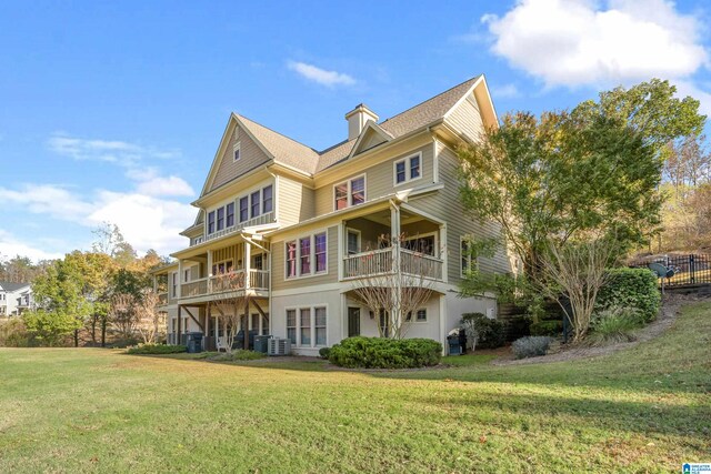 rear view of house featuring a lawn, a balcony, and central AC unit