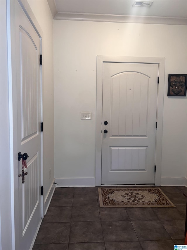 entryway featuring dark tile patterned floors and ornamental molding