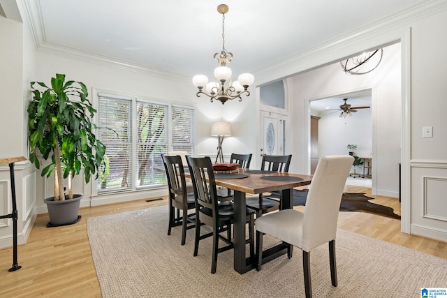 dining space with ceiling fan with notable chandelier, crown molding, and light hardwood / wood-style flooring