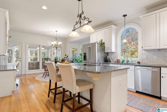 kitchen with light wood-type flooring, stainless steel appliances, white cabinetry, and plenty of natural light