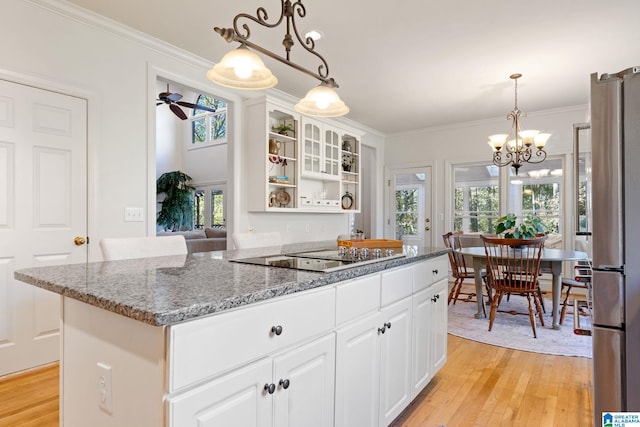 kitchen with ceiling fan with notable chandelier, stainless steel fridge, light wood-type flooring, black electric cooktop, and white cabinetry