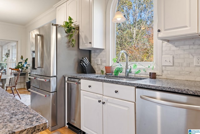 kitchen with stainless steel appliances, crown molding, sink, white cabinets, and light hardwood / wood-style floors