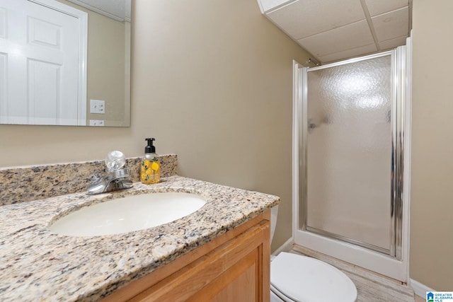 bathroom featuring wood-type flooring, an enclosed shower, toilet, a paneled ceiling, and vanity