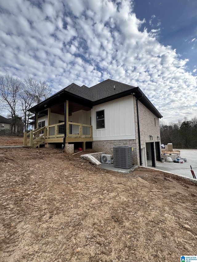 view of side of property featuring a garage, central AC unit, and a patio area