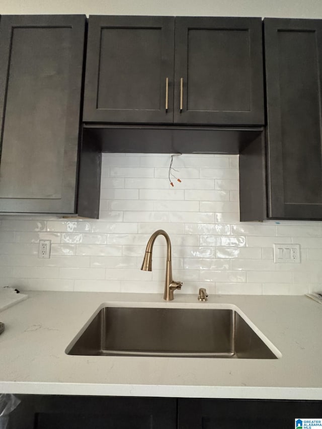 kitchen featuring tasteful backsplash, sink, and light stone counters