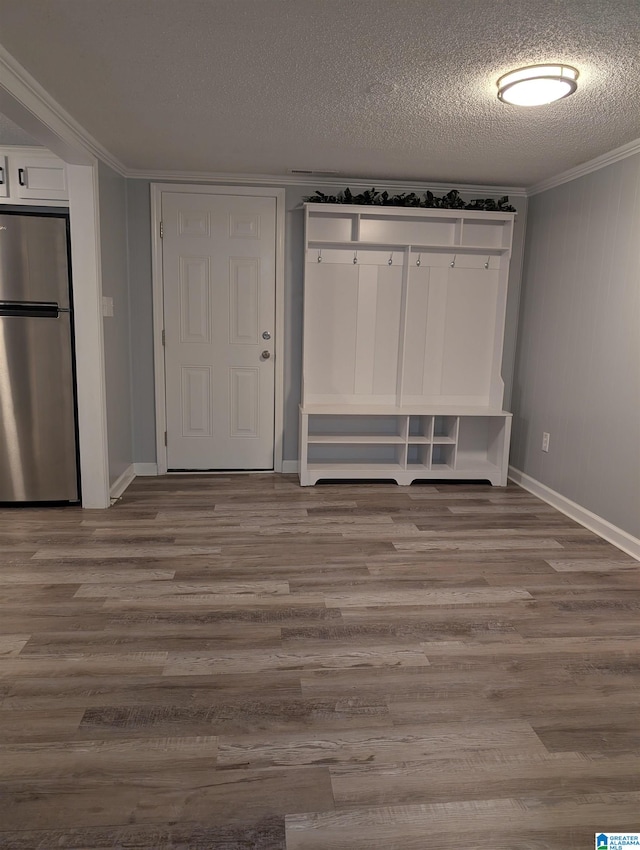 interior space with stainless steel fridge, a textured ceiling, light hardwood / wood-style floors, and crown molding