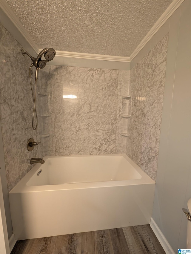 bathroom featuring hardwood / wood-style flooring, ornamental molding, tiled shower / bath, and a textured ceiling