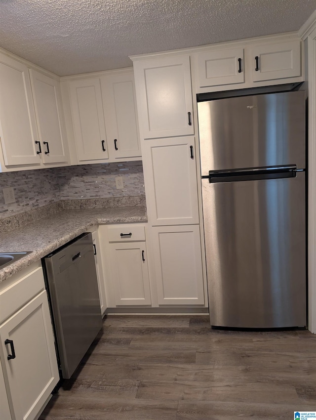 kitchen featuring backsplash, white cabinetry, stainless steel appliances, and dark hardwood / wood-style floors