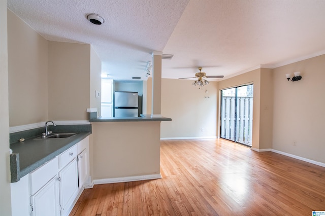 kitchen with ceiling fan, sink, kitchen peninsula, stainless steel fridge, and light wood-type flooring