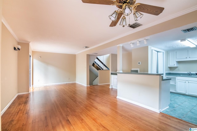 unfurnished living room with light hardwood / wood-style floors, ceiling fan, crown molding, and sink