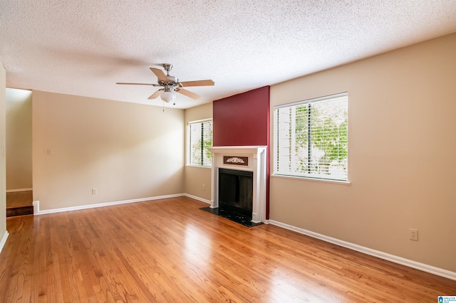 unfurnished living room with ceiling fan, light wood-type flooring, and a textured ceiling