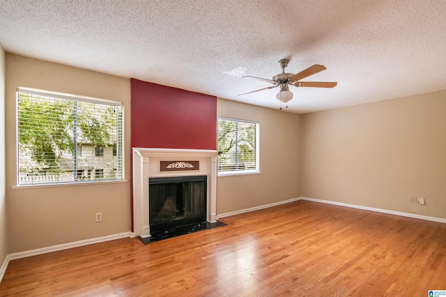 unfurnished living room featuring ceiling fan, light wood-type flooring, and a textured ceiling