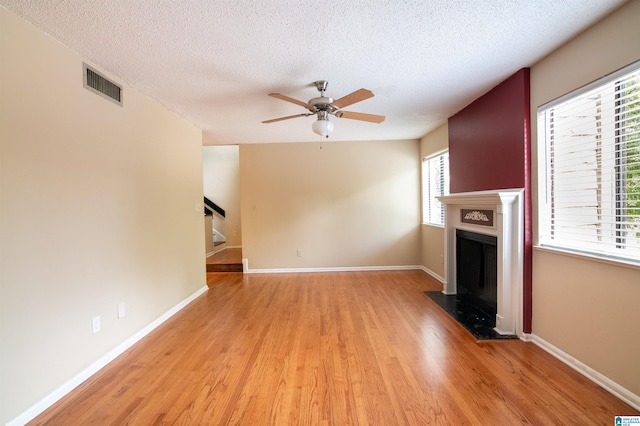 unfurnished living room featuring ceiling fan, light hardwood / wood-style floors, and a textured ceiling