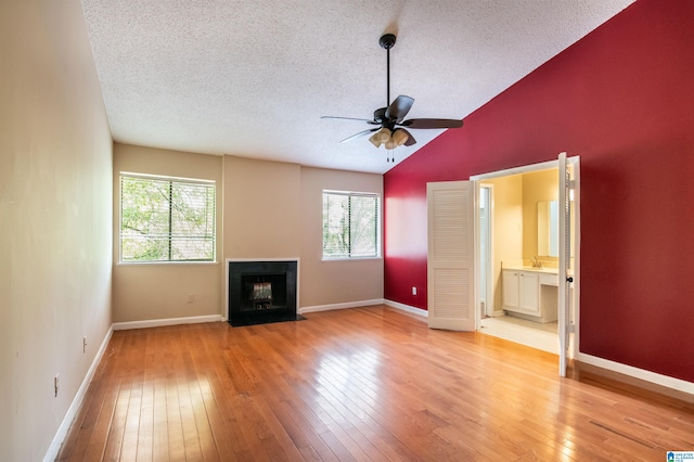 unfurnished living room with ceiling fan, a healthy amount of sunlight, light wood-type flooring, and a textured ceiling