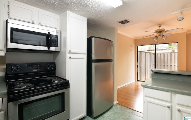 kitchen featuring white cabinetry, ceiling fan, a textured ceiling, appliances with stainless steel finishes, and ornamental molding