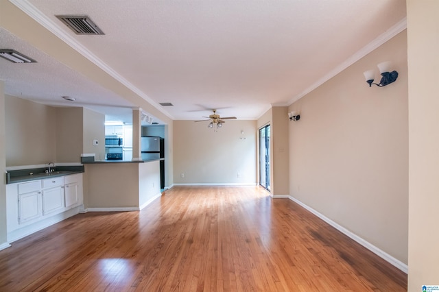 unfurnished living room with a textured ceiling, ceiling fan, crown molding, sink, and light hardwood / wood-style floors