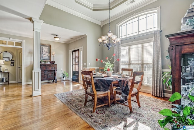 dining room featuring a chandelier, decorative columns, light hardwood / wood-style flooring, and ornamental molding