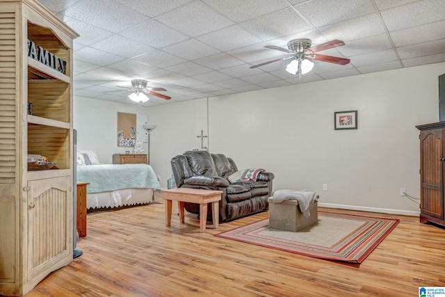 bedroom featuring ceiling fan, a drop ceiling, and light hardwood / wood-style flooring