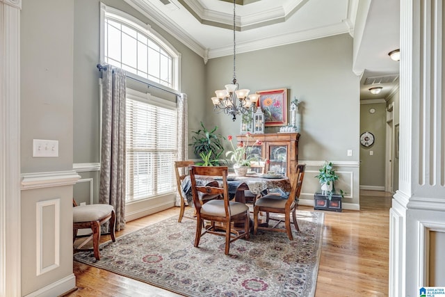 dining area featuring a chandelier, decorative columns, crown molding, and light hardwood / wood-style flooring