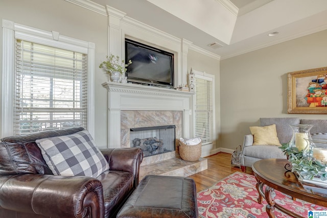 living room with light wood-type flooring, crown molding, and a high end fireplace