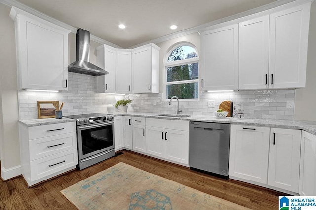 kitchen featuring white cabinetry, wall chimney range hood, sink, and appliances with stainless steel finishes