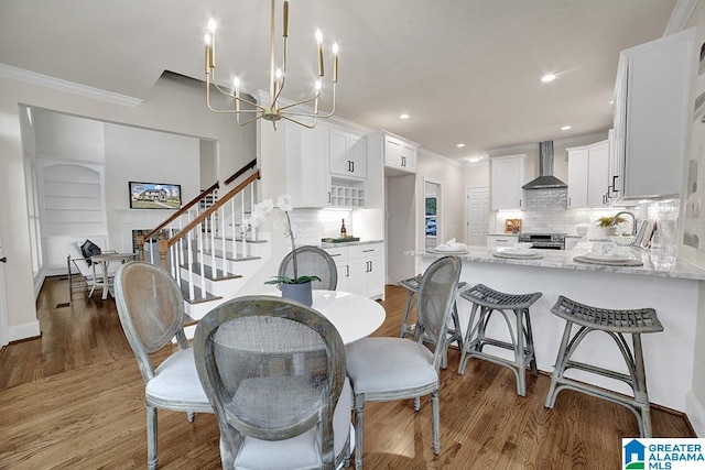 dining area with ornamental molding, a notable chandelier, and hardwood / wood-style flooring