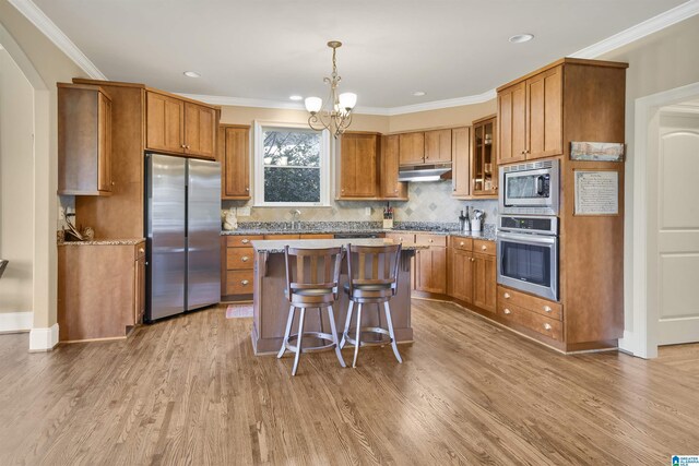 2399 Huntington Glen Dr, Homewood, AL 35226 - kitchen featuring stainless steel appliances, brown cabinets, a chandelier, light wood-style flooring, and ornamental molding