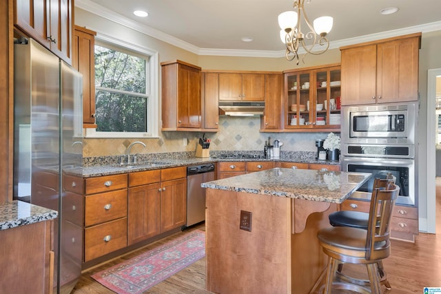 kitchen with appliances with stainless steel finishes, stone counters, a chandelier, a center island, and hanging light fixtures