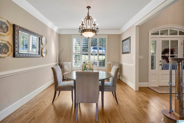 dining space with light wood-type flooring, ornamental molding, and an inviting chandelier