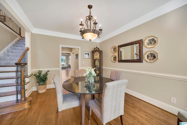 dining space featuring a chandelier, wood-type flooring, and ornamental molding