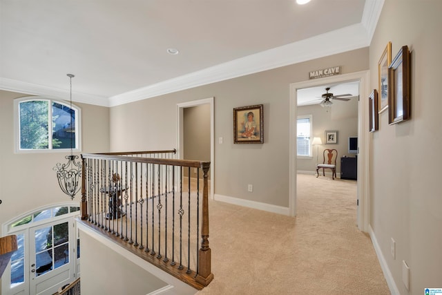 corridor featuring light carpet, french doors, a wealth of natural light, and crown molding