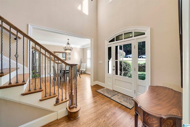 entrance foyer featuring a chandelier, hardwood / wood-style floors, ornamental molding, and a high ceiling