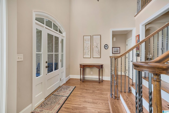 foyer with french doors, light hardwood / wood-style flooring, and a high ceiling