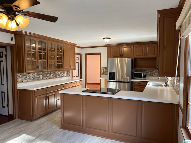 kitchen with kitchen peninsula, decorative backsplash, stainless steel appliances, sink, and light hardwood / wood-style floors