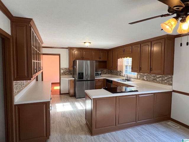 kitchen featuring sink, light hardwood / wood-style flooring, backsplash, kitchen peninsula, and stainless steel fridge