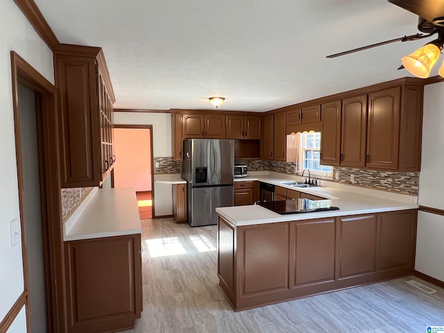 kitchen with stainless steel fridge, kitchen peninsula, sink, and tasteful backsplash