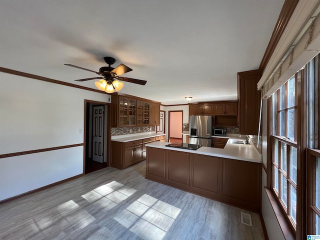 kitchen with ceiling fan, stainless steel appliances, backsplash, kitchen peninsula, and ornamental molding