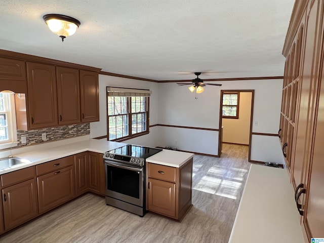 kitchen featuring stainless steel electric range, a healthy amount of sunlight, kitchen peninsula, and light hardwood / wood-style flooring