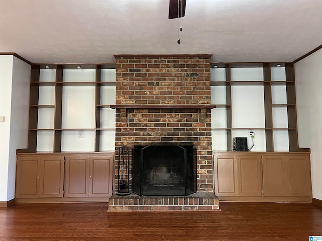 unfurnished living room featuring a textured ceiling, crown molding, dark wood-type flooring, and a brick fireplace