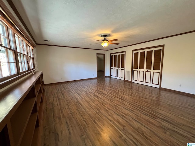 unfurnished living room with ceiling fan, dark hardwood / wood-style flooring, ornamental molding, and a textured ceiling