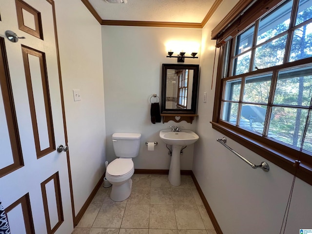 bathroom with tile patterned flooring, toilet, ornamental molding, and a textured ceiling