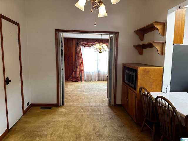 corridor featuring light carpet and a notable chandelier