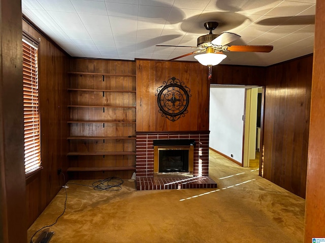 unfurnished living room featuring ornamental molding, light colored carpet, ceiling fan, a fireplace, and wood walls