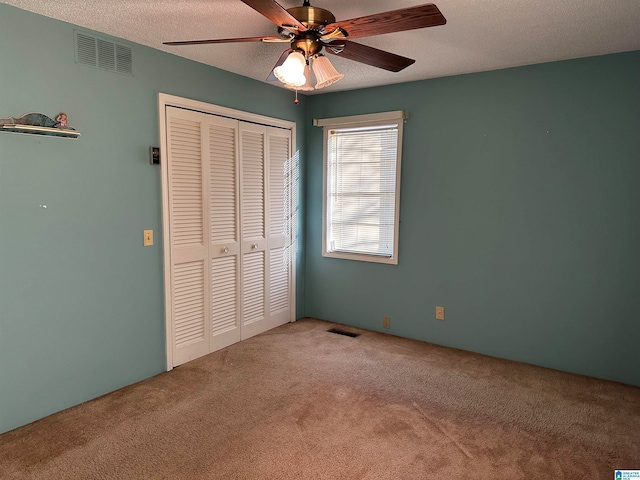 unfurnished bedroom featuring carpet flooring, ceiling fan, a textured ceiling, and a closet