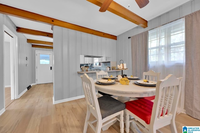 dining space with beam ceiling, ceiling fan, and light wood-type flooring