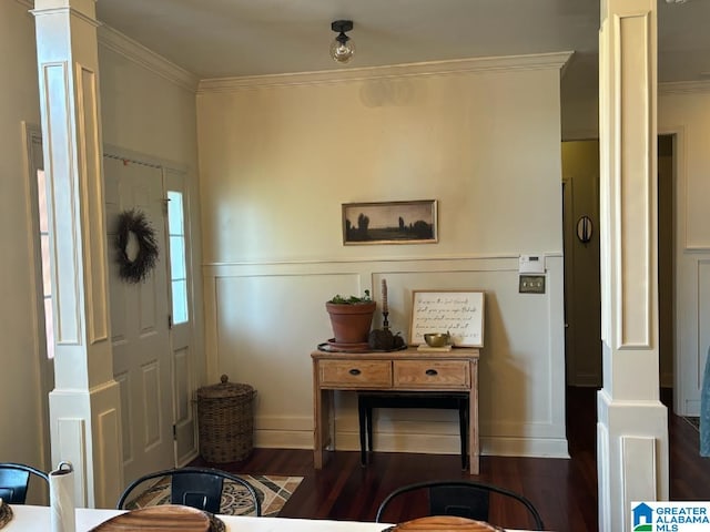 foyer entrance featuring dark hardwood / wood-style flooring, ornamental molding, and decorative columns