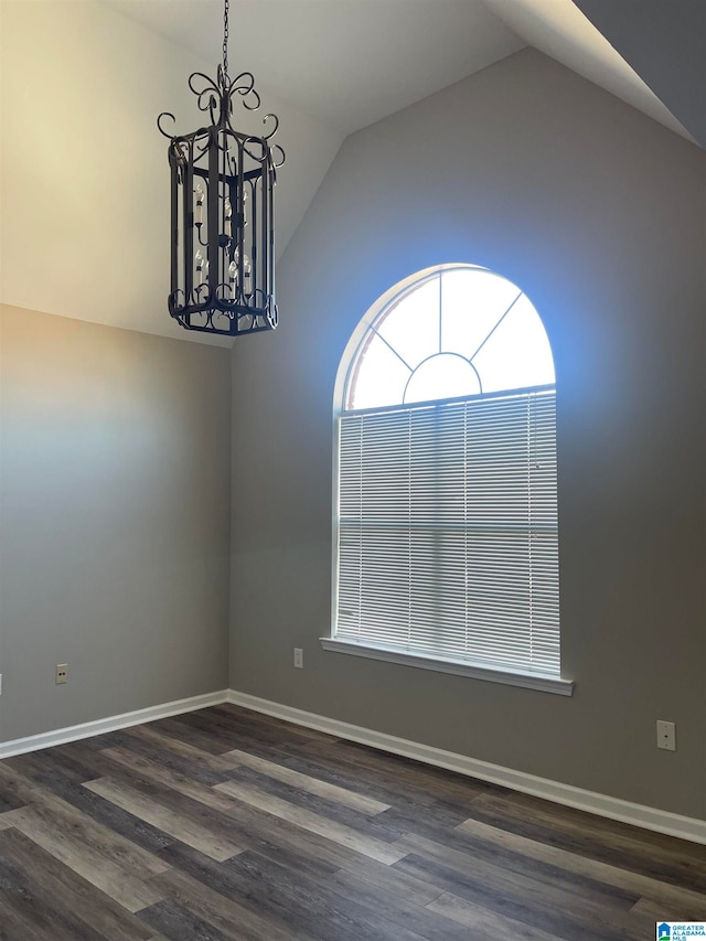 empty room featuring dark hardwood / wood-style flooring, lofted ceiling, and a notable chandelier