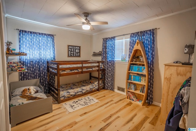 bedroom with ceiling fan, wood-type flooring, and ornamental molding