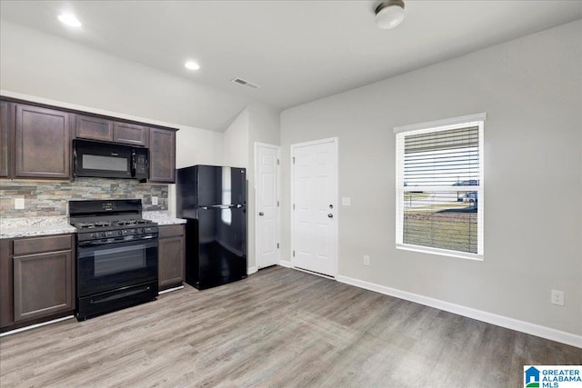 kitchen featuring dark brown cabinetry, tasteful backsplash, light stone counters, light hardwood / wood-style flooring, and black appliances